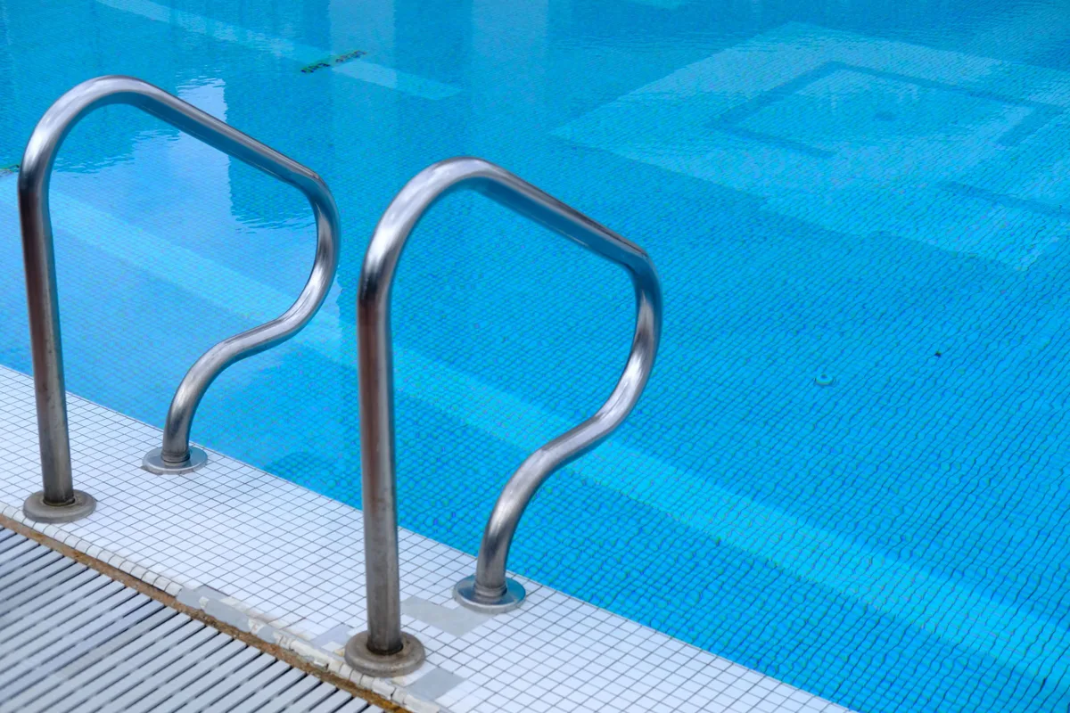 Stainless steel pool ladder rails over clear water